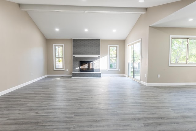 unfurnished living room featuring lofted ceiling with beams, a brick fireplace, and hardwood / wood-style flooring