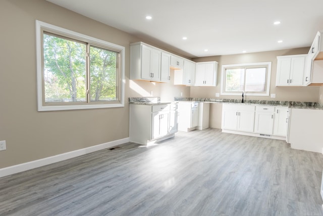 kitchen featuring white cabinetry, light wood-type flooring, and plenty of natural light