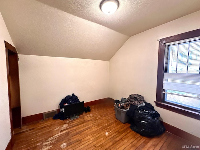 bonus room with lofted ceiling, a textured ceiling, and wood-type flooring