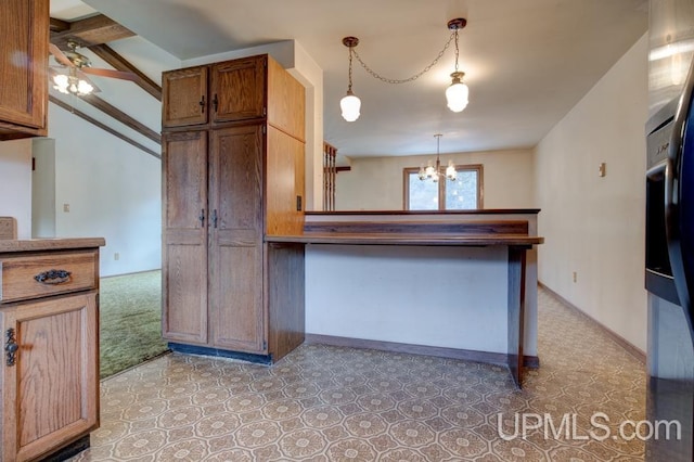 kitchen featuring beam ceiling, carpet, pendant lighting, and ceiling fan with notable chandelier