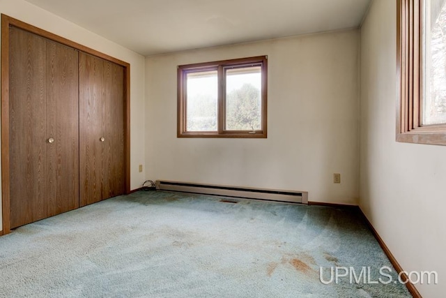 unfurnished bedroom featuring light carpet, a closet, and baseboard heating