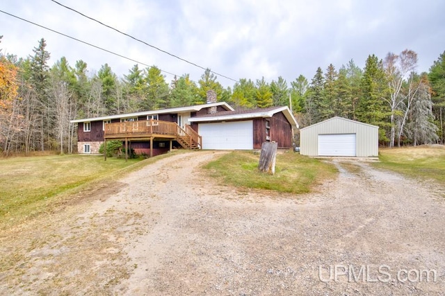 view of front facade featuring an outdoor structure, a front yard, a wooden deck, and a garage