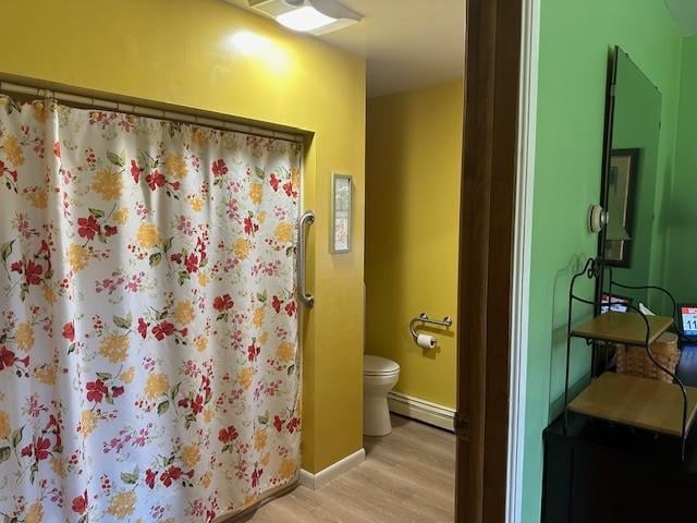 bathroom featuring toilet, hardwood / wood-style flooring, and baseboard heating