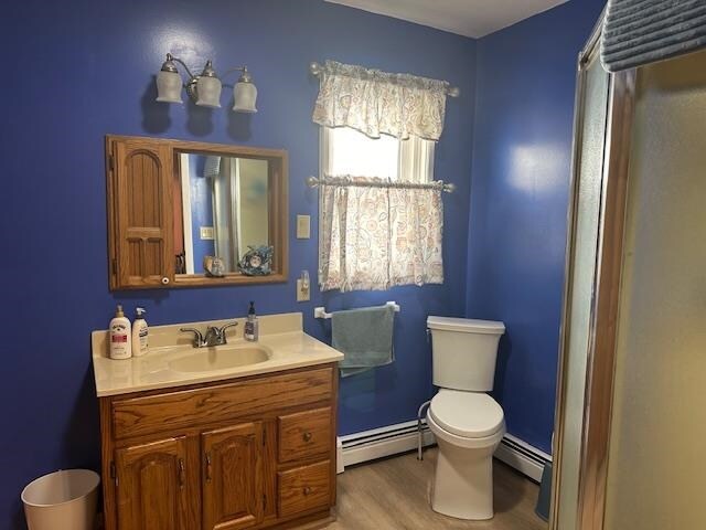 bathroom featuring vanity, toilet, a baseboard radiator, and hardwood / wood-style floors