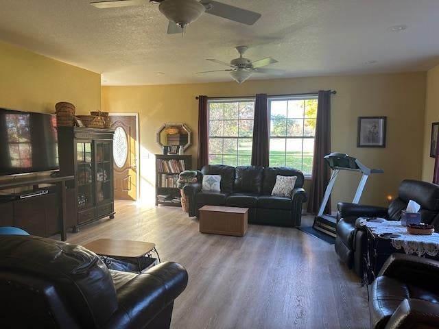 living room featuring a textured ceiling, wood-type flooring, and ceiling fan