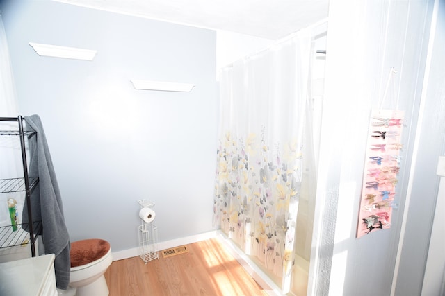 bathroom with toilet, shower / tub combo with curtain, and wood-type flooring