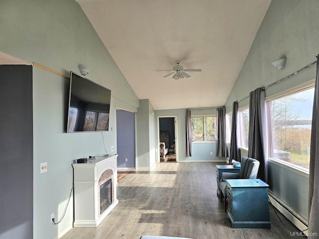 living area with hardwood / wood-style flooring, ceiling fan, lofted ceiling, and baseboard heating