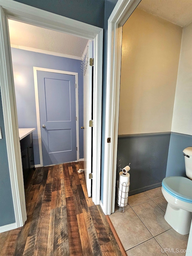 bathroom featuring hardwood / wood-style flooring, vanity, toilet, and ornamental molding