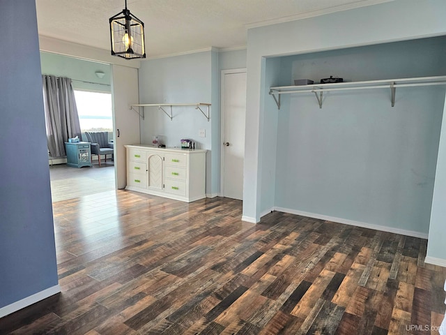 unfurnished bedroom featuring crown molding, dark hardwood / wood-style flooring, an inviting chandelier, and a baseboard heating unit