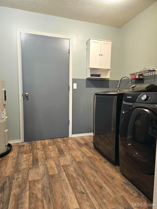 laundry room with cabinets, electric water heater, hardwood / wood-style flooring, independent washer and dryer, and a textured ceiling