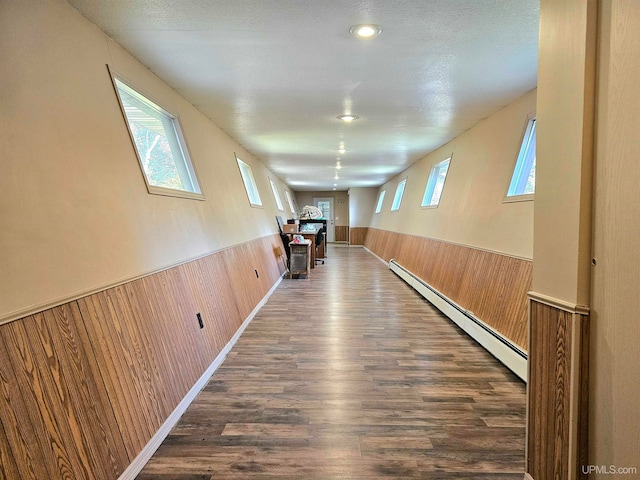 corridor featuring a textured ceiling, dark hardwood / wood-style flooring, and a baseboard radiator