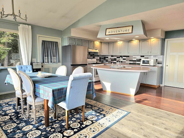 dining room featuring sink, vaulted ceiling, and hardwood / wood-style flooring