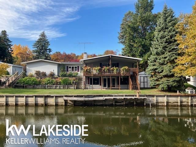 back of house featuring a shed, a deck with water view, and a lawn