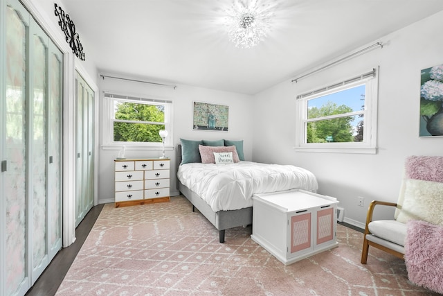 bedroom featuring light hardwood / wood-style flooring, a notable chandelier, and multiple windows