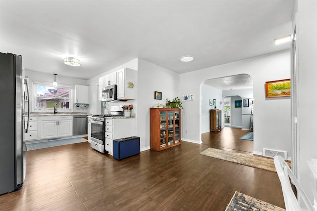 kitchen featuring sink, hanging light fixtures, white cabinetry, stainless steel appliances, and dark wood-type flooring