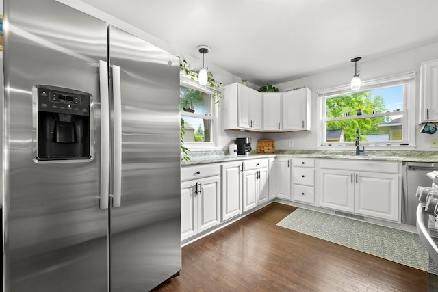 kitchen with stainless steel refrigerator with ice dispenser, white cabinets, sink, and pendant lighting