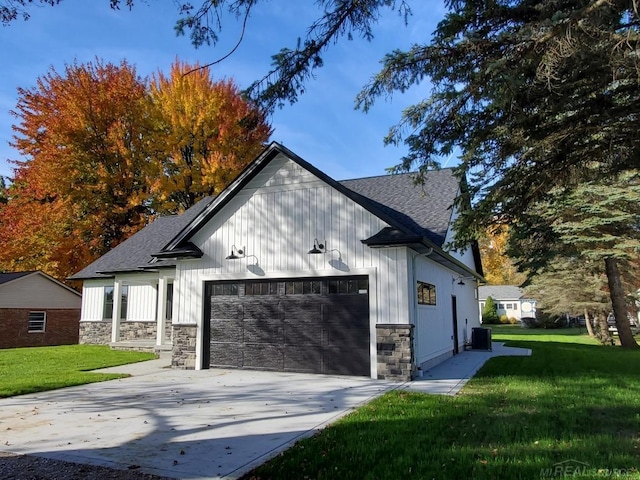 view of side of property with central air condition unit, a yard, and a garage