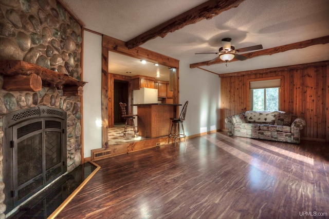 unfurnished living room featuring ceiling fan, a fireplace, a textured ceiling, and dark hardwood / wood-style flooring