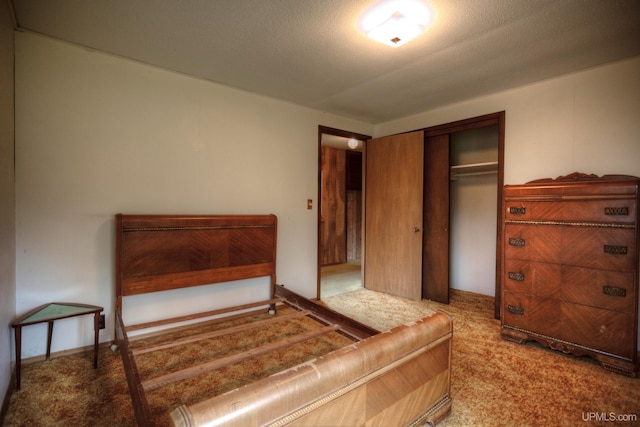 bedroom with a textured ceiling, carpet flooring, and a closet