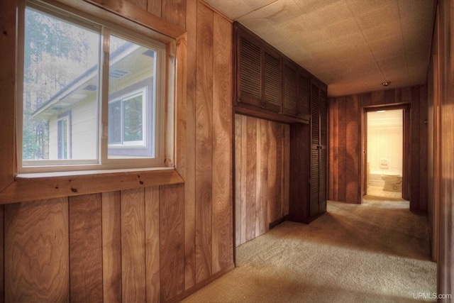 hall featuring wood walls and light colored carpet