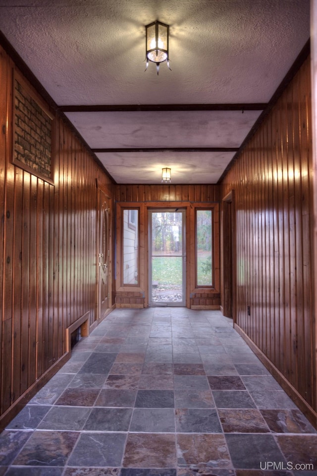 hallway featuring a textured ceiling and wood walls