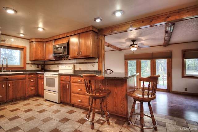 kitchen with kitchen peninsula, a wealth of natural light, sink, and white range with electric cooktop