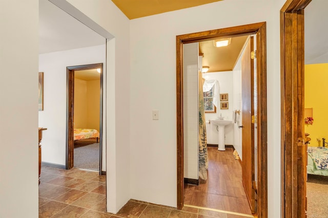 hallway featuring sink and dark colored carpet