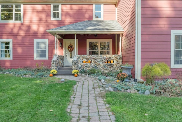 doorway to property with covered porch and a yard