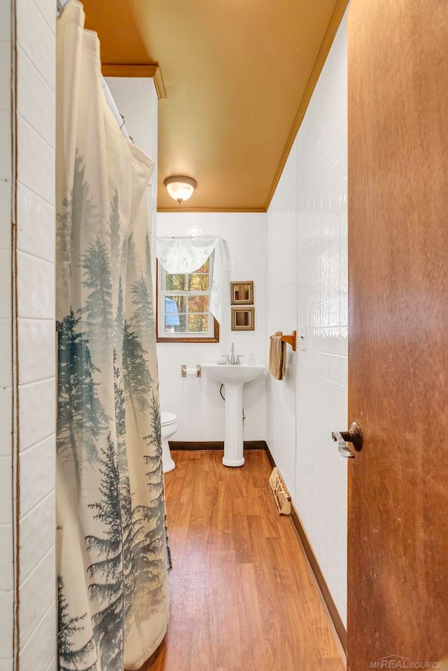 bathroom featuring toilet, wood-type flooring, ornamental molding, and a shower with curtain