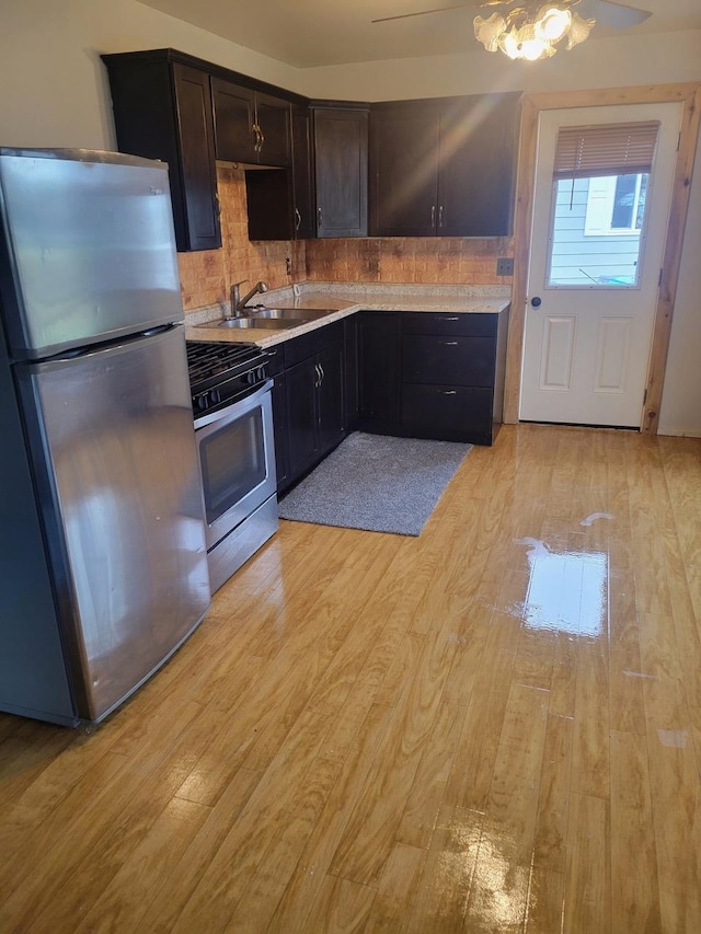 kitchen with light hardwood / wood-style floors, decorative backsplash, stainless steel appliances, and sink