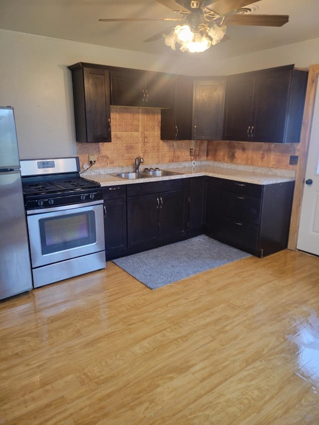 kitchen featuring ceiling fan, backsplash, light hardwood / wood-style flooring, sink, and stainless steel appliances