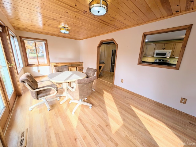 dining room featuring arched walkways, wooden ceiling, light wood-style flooring, and baseboards