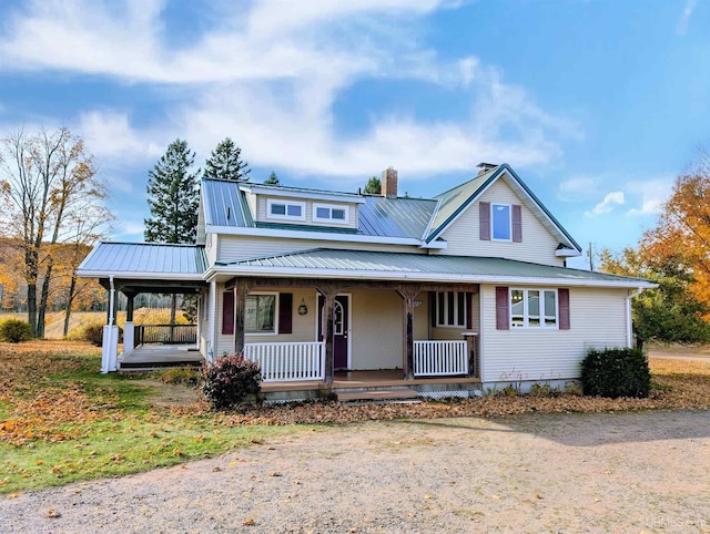 farmhouse inspired home featuring a chimney, a porch, and metal roof