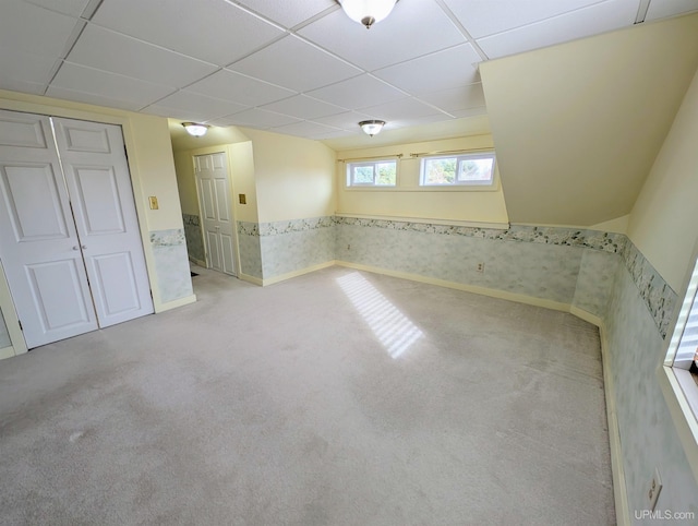 below grade area with carpet, a paneled ceiling, and wallpapered walls