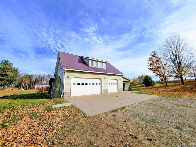 view of side of property with concrete driveway, metal roof, and a lawn