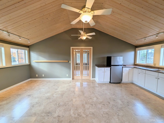 kitchen featuring freestanding refrigerator, rail lighting, wood ceiling, french doors, and dark countertops
