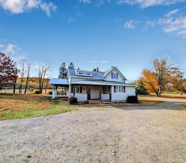 view of front of property featuring covered porch, dirt driveway, metal roof, and an attached carport