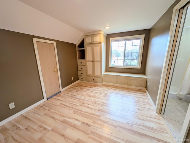 unfurnished bedroom with light hardwood / wood-style floors, lofted ceiling, radiator heating unit, and connected bathroom