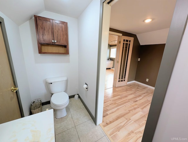 bathroom with toilet, lofted ceiling, and wood-type flooring