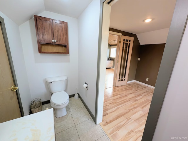 bathroom featuring lofted ceiling, toilet, and baseboards