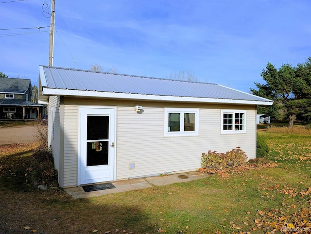 back of house featuring a lawn and metal roof