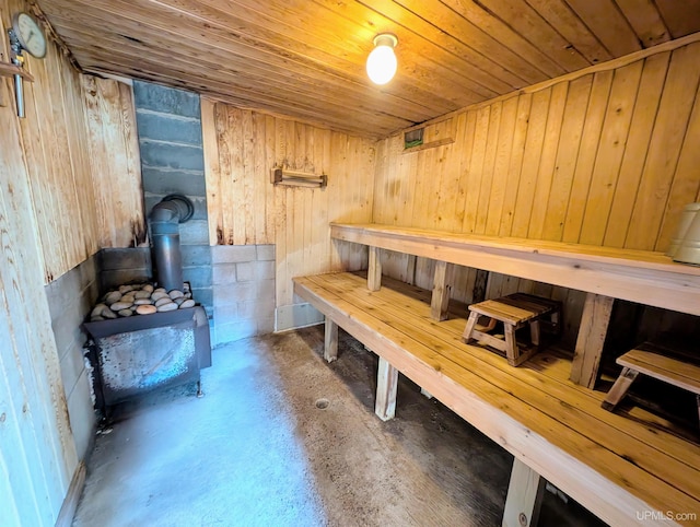 relaxing sauna / steam room featuring concrete flooring, wooden ceiling, and wood walls