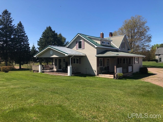 rear view of property with covered porch and a lawn