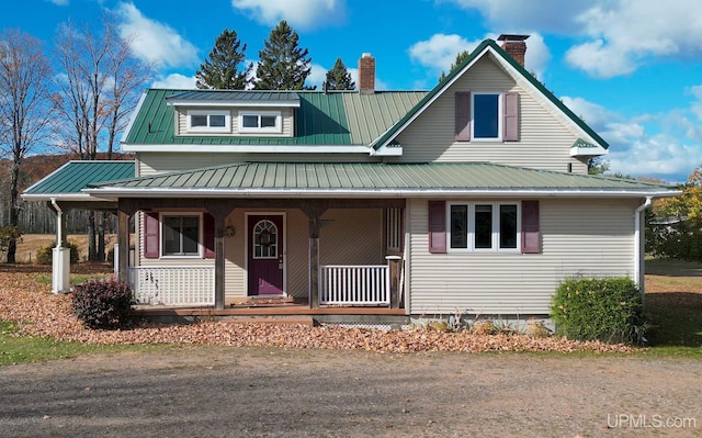 farmhouse with a chimney, a porch, and metal roof