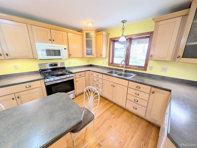 kitchen with light brown cabinetry, sink, light hardwood / wood-style floors, pendant lighting, and stainless steel gas range oven