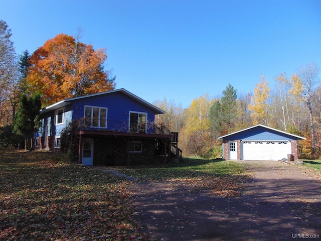 view of home's exterior with a detached garage, an outdoor structure, a deck, and stairway