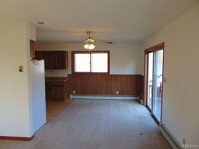 carpeted spare room featuring a healthy amount of sunlight, a baseboard radiator, and ceiling fan