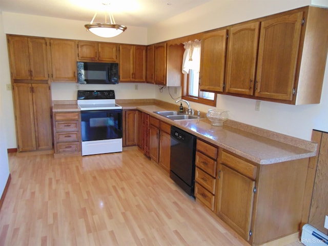 kitchen with a baseboard heating unit, light hardwood / wood-style flooring, black appliances, decorative light fixtures, and sink