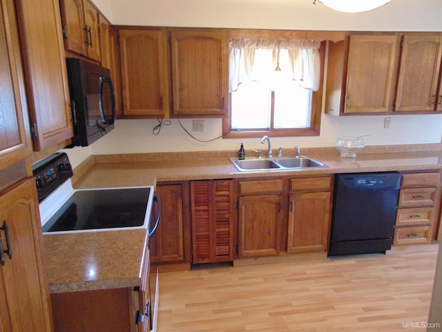 kitchen featuring sink, black appliances, and light hardwood / wood-style flooring