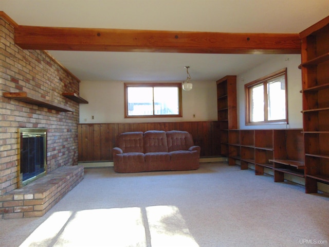 living room with wooden walls, light carpet, a brick fireplace, and plenty of natural light